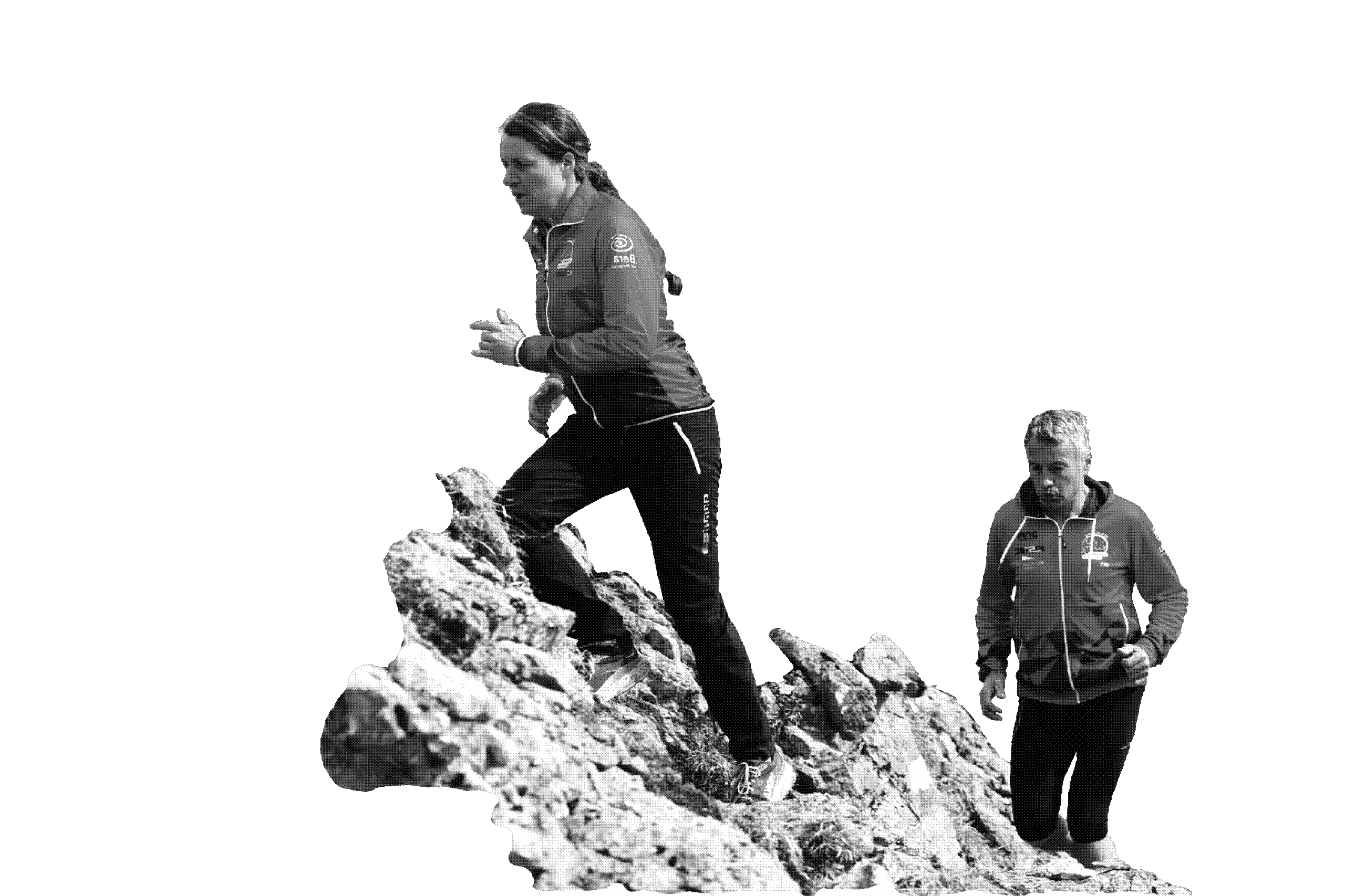 Eine Läuferin und ein Läufer laufen über einen Fels.